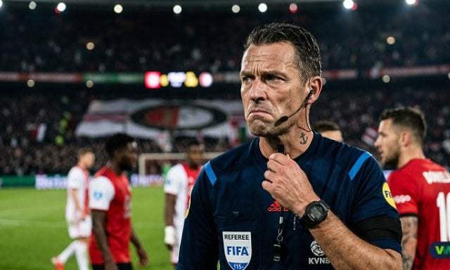 Een geconcentreerde voetbalscheidsrechter met een fluitje op het veld tijdens een wedstrijd, illustratie voor De onzichtbare fluit: Hoe scheidsrechters onbewust wedstrijden beïnvloeden.